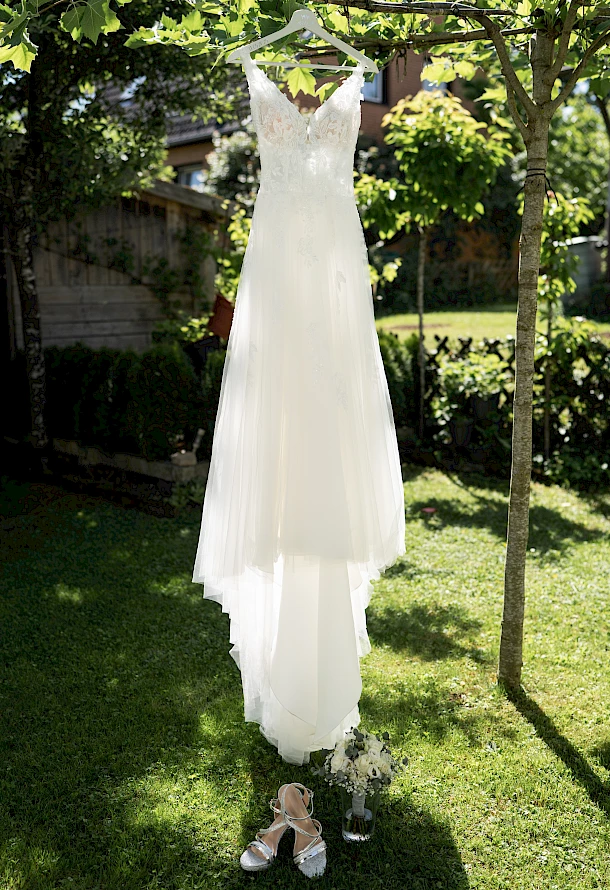 Detailaufnahme vom Brautkleid das im Garten in der Sonne hängt