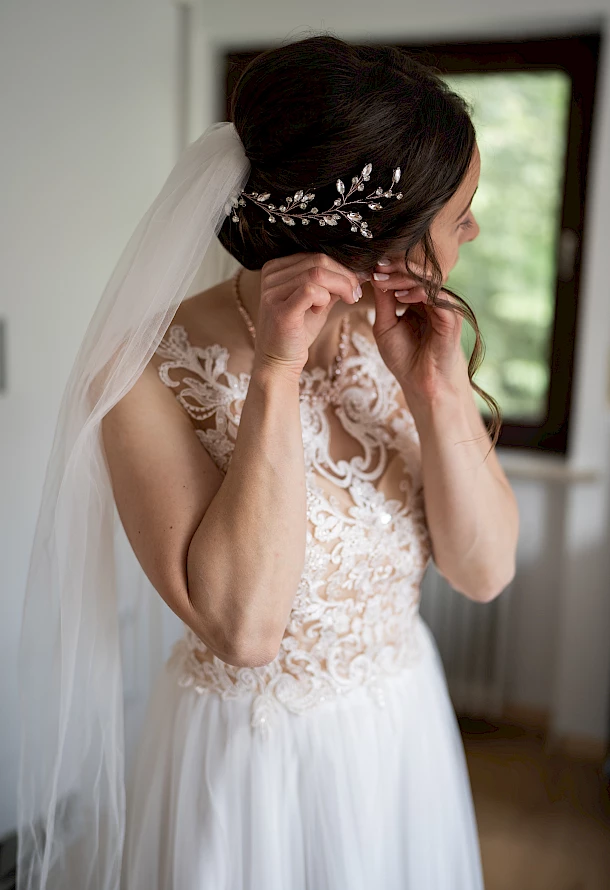 Braut beim Anstecken der Ohrringe im Hotelzimmer am Leineckstausee