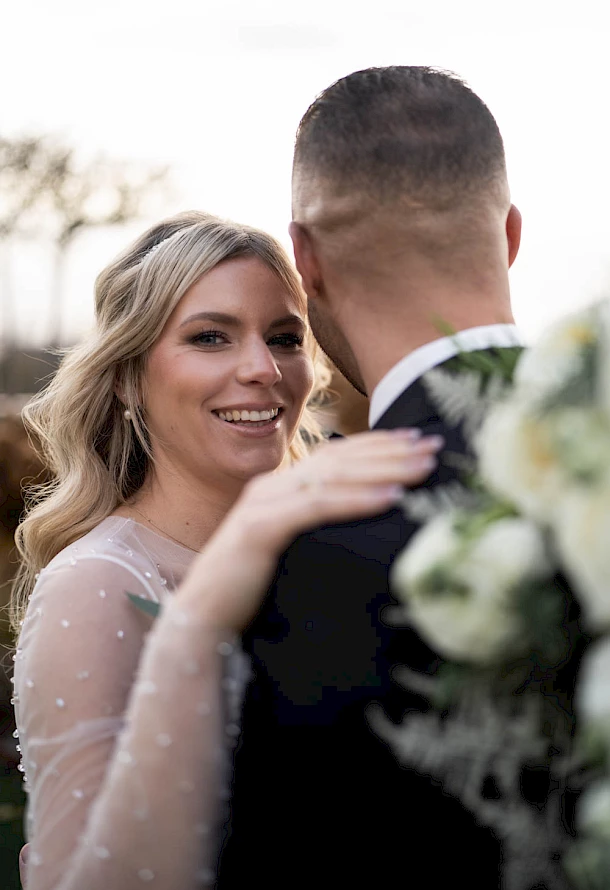 Lächelnde Braut in den Armen von ihrem Bräutigam