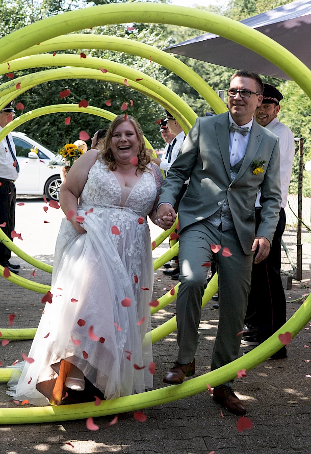 Brautpaar läuft durch Spalier der Feuerwehr mit Rosenblättern