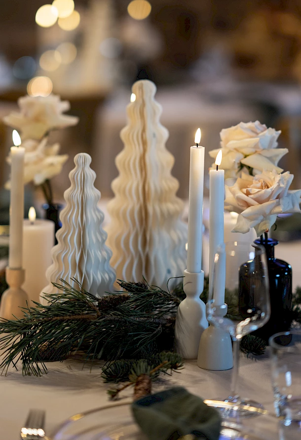 Detailaufnahme von weihnachtlicher Dekoration mit kleinen Weihnachtsbäumen und Kerzen