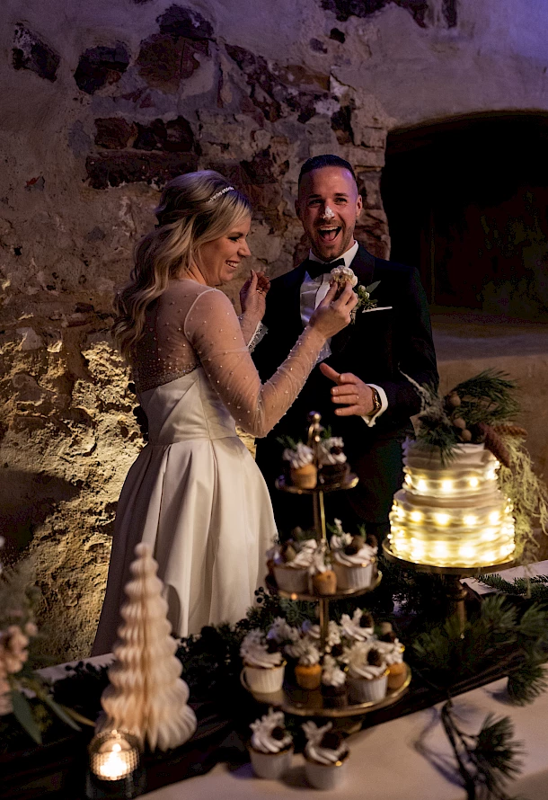Brautpaar lacht herzlich beim Anschnitt der Torte auf Burg Staufeneck