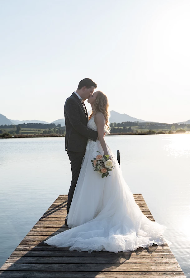 Inniger Kuss auf dem Bootssteg beim After Wedding Shooting vor Bergpanorama im Allgäu