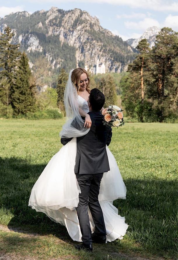 Bräutigam trägt seine Braut auf Händen vor einer Bergkulisse im Allgäu beim After Wedding Shooting